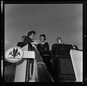 Sen. Barry Goldwater addressing the crowd at the airport from the American Airlines stair ramp of the plane while his wife Peggy receives flowers