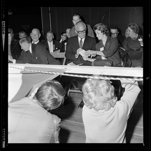 Sen. Barry Goldwater talking with his wife Peggy as two youngsters look underneath the stage curtains at Fenway Park