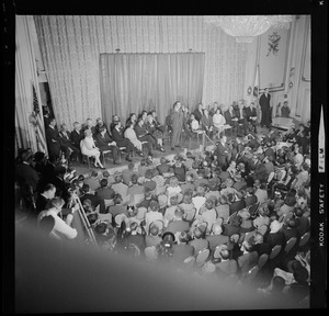 Nixon speaks on stage to a full audience