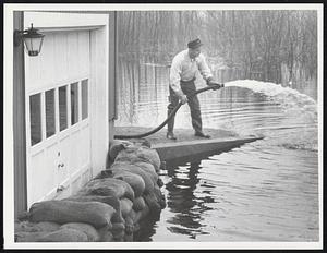 Pumping the Concord River out of his cellar is T. Robert Primmerman of 16 Sheridan Rd., Bedford. Like many of his neighbors, Primmerman had to evacuate his family because of the flood.