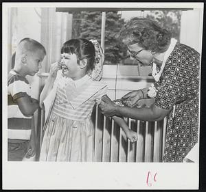 Brave Sue Ann Ivarson, 7, grasps nose between her fingertips trying to keep from crying as she receives polio vaccine shot in Denver. Schoolmate at left looks a bit apprehensive. He’s next.