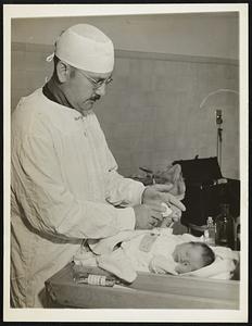 This Roto Picture For Release November 22. New system for prevention of baby mixups palm print technique of identification has been developed by Dr. Gilbert P. Pond of West Suburban Hospital of Chicago, Ill., to prevent mixups in identification of babies. Photo no. 1 of this series shows Dr. Pond washing birth moisture from the hand of the infant before palm testing,