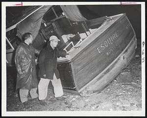 Washed Ashore In Storm - Ollie Aldrich (left) and Ralph Lincoln look over the boat, "Esquire" washed ashore in front of the Savin Hill Yacht Club by last night's mile-a-minute winds.