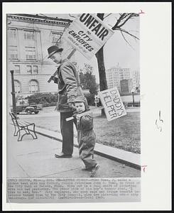 Little Picket--Mike Toms, 2, walks a picket beat with his father, Police Patrolman John S. Toms, in front of the City Hall at Duluth, Minn. Mike put in a full shift of picketing with his dad yesterday. The other side of the boy's banner read, "I like to eat, too." City employes, who seek wage and fringe benefit increases turned down by the City Council, also are picketing other city buildings.