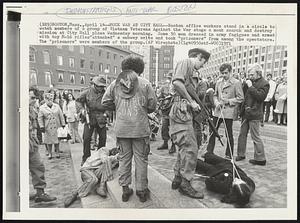 Mock War at City Hall--Boston office workers stand in a circle to watch members of a group of Vietnam Veterans Against the War stage a mock search-and-destroy mission at City Hall plaza Wednesday morning. Some 30 men dressed in army fatigues and armed with toy M-16 rifles "attacked” a subway exits and took “prisoners” from among the spectators. The “prisoners” were members of the group.