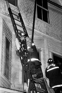 Firefighters Bob Kinsella and John Dodd scaling ladders to vent the third floor