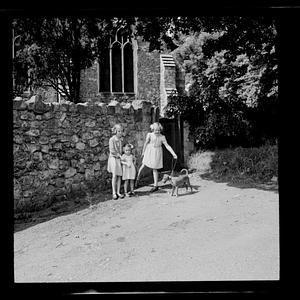 Three children and dog standing in garden