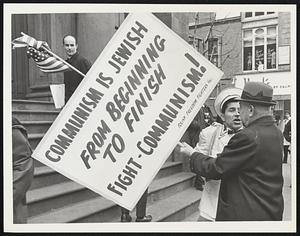 Josef Mlot-Mroz speaking with an unidentified man, holding a sign which states "Communism is Jewish from beginning to finish Fight-Communism! Polish Freedom Fighters Inc."