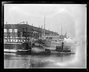 USS Topeka, a tugboat next to it