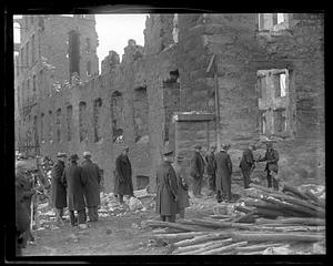 People examining debris after a disaster, possibly a fire