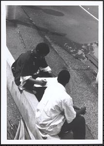 Junior Gabriel (on left) and another young man sitting and writing