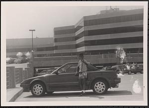 Boy posing in front of a car in a parking lot