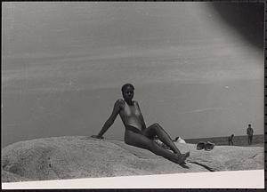 A young woman sitting on a rock at the beach
