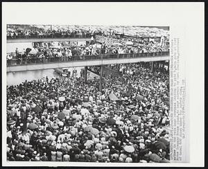 Detroit – Ford Strikers Hold Mass Meeting – UAW strikes gather in the rain near overpass leading to gate 4, main gate at Ford Motor Company Rouge plant, to hear address by Carl Stellato, president of Local 600 shown under the safety sign.