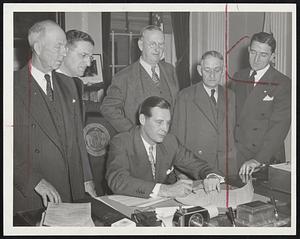 First Bill Enacted by Legislature – Permitting cities and towns to celebrate return of veterans, is signed at the State House yesterday by Gov. Tobin. Standing, left to right, Rep. Elmer McCullock, Adams; Harry Kalus, counsel to Governor; Senator Michael H. Condron, Pittsfield; Rep. Joseph Roach, North Adams, and Senator Chester A. Dolan, Boston.