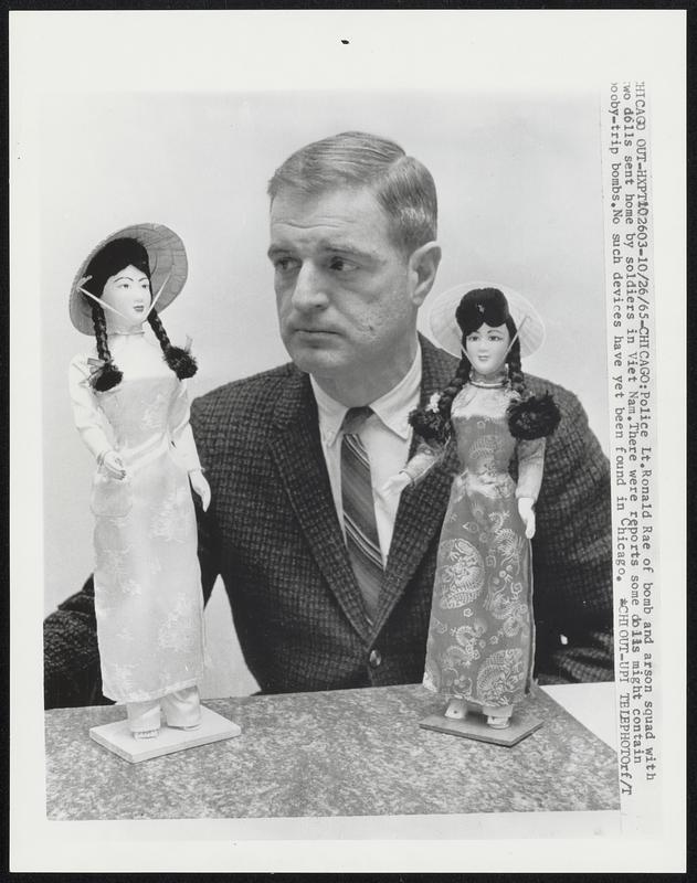 Police Lt.Ronald Rae of bomb and arson squad with two dolls sent home by soldiers in Viet Nam.There were reports some dolls might contain booby-trip bombs.No such devices have yet been found in Chicago.