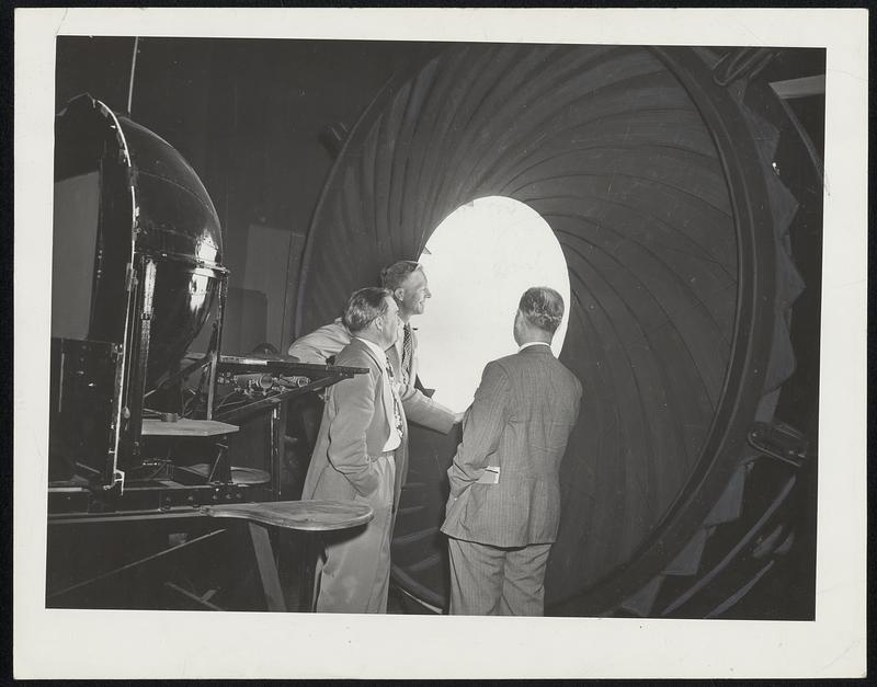 Light Intensity of Lighting Fixtures is measured by this giant hemispherical integrator on exhibit at the Lighting Specialists Conference at the Lynn River Works of General Electric. Here, A. M. Bjontegaard (center), GE engineer explains device to A. W. Carry of Kansas City, Mo., and L. C. Loronzen of Chicago, Ill