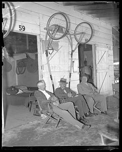 Men sitting in front of harness racing carts