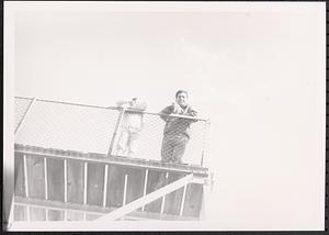Two young men leaning on fence, shot from below