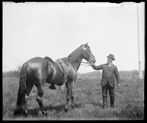 Man holding horse (saddled)