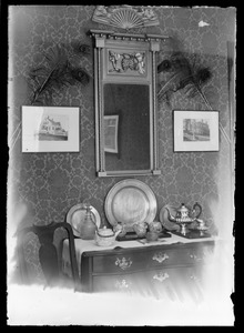 Scene of one wall in dining room of a home with bureau, mirror and pictures