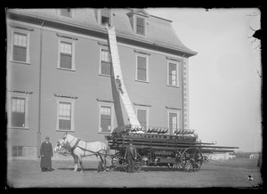 Man sliding down chute from 3rd story of Agricultural Hall and horse drawn fire wagon