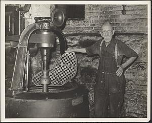 Dalton Woolen Mill (Sawyer Regan), employee standing at the machine which extracts water from the cloth after it has been scoured