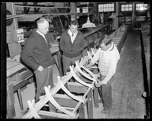 Coach Charles Whiteside, Harvard Crew, look down at a boat being built