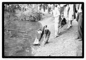 Boy sending out model sailboat