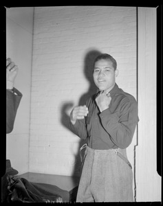 Joe Louis takes off his street clothes before fight with Al McCoy, at Boston Garden