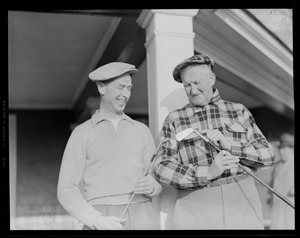 Two old golfers inspect their clubs