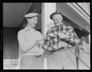 Two old golfers inspect their clubs