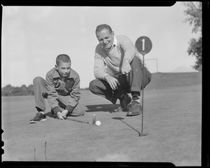 Men showing boy how to line up a putt