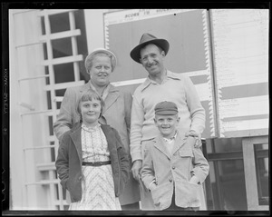 Man & woman and two children pose in front of scoreboard on clubhouse