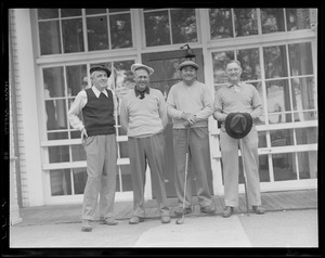 Four golfers pose in front of clubhouse