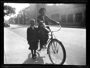 Two boys, one riding a bicycle