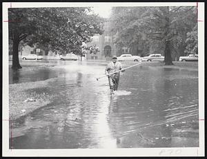 Raking Rising Water is not the usual way to combat a hurricane, but this park department employe finds this tool handy. He is cleaning the catch basins on Playstead Rd., Jamaica Plain.