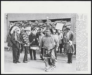 Indian War Dance - While a group of cowboy hat-wearing Sioux Indians (rear) beat out the rhythm on a modern "tom-tom," Victor Young Bear, Sioux tribal leader from Standing Rock Reservation of North and South Dakota, does a war dance today in front of the former county Agricultural Stabilization and Conservation office. The Indians showed up to help Mound Citians protest the federal government's moving records to nearby Herreid. The records are in the sand-bagged building at rear. Another tribal leader stands with peace pipe at left.