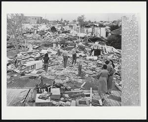 Survey Storm Damage--Residents start the cleanup job in this tornado-wrecked city today following the storm yesterday and a night of torrential rains. Some are shown surveying the destruction while others start probing through what is left of their house in search of possessions. The storm left 2 dead and some 100 injured. Olney's mayor, E.C. Hallman, estimated damage at $1,500,000 or more. 54 homes were totally destroyed and 132 were damaged in varying degrees. 5 business buildings were completely destroyed and 21 damaged. The storms narrowly missed the city's school shown in upper left as it cut a 200-yard wide swath through the western part of the town.