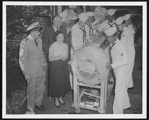 First of 10 Iron Lungs released yesterday by Navy to National Foundation for Infantile Paralyses for use in polio emergency leaves Iron Lung Company of America, Roxbury. From left, Lt. Daniel D. Gallagher, First Naval District; Joan Kerrigan, company secretary; and James M. Connolly, chairman of the Suffolk County Chapter, NFIP.