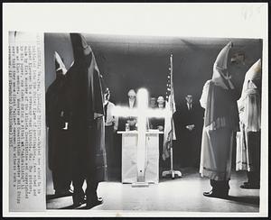 Klan Initiates--Masked men about to be initiated into the United Klans of America, Inc., face robed and masked Klansmen in a ceremony near Lithonia, Ga. The picture made by Kirk Wooster of the Atlanta Constitution and copyrighted by his paper, was taken during a ritual "naturalizing" 11 men as Klan members. Wooster and Constitution reporter Bill Shipp were told they were first "alien" newsmen to witness such ceremony.