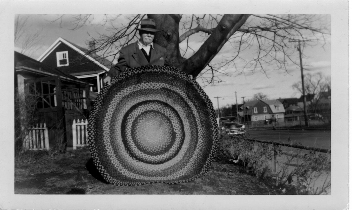 Braided rug made by Ora Baker, 1955, held by a gentleman.