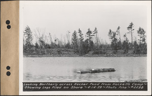 Looking northerly across Hacker Pond from Hackett's Camp, showing logs piled on shore, New Salem, Mass., Apr. 14, 1939