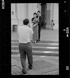 Formally dressed couple being photographed, possibly after a civil wedding