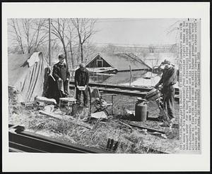 Ready to Break Camp - Floodwaters even with the eaves of his house (background), Fred Fulweiler (right) tunes up his outboard motor for a hasty retreat as Mississippi river continued to rise. Prospects are that Fulweiler and his two flooded-out neighbors will have to flee with their tent to still higher ground. With water already up to the railroad track, engineers forecast the stream would rise another foot.