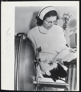 Mother Has Child in Iron Lung- A Three-pound daughter was born Christmas day to Mrs. Iva Hitchcox. 37, infantile paralysis victim in Battle Creek, Mich., confined to an iron long for 14 weeks. Above, a nurse reads Mrs. Hitchcock a letter from her husband, Capt. G Hobart Hitchcox, on the Western Front.