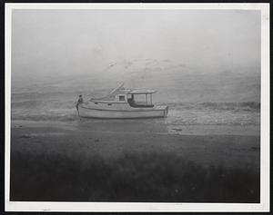 Clings To Boat Washed Ashore-An unidentified man clings to a cabin cruiser washed ashore at Wollaston Beach.