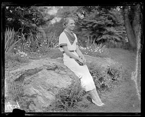 An unidentified woman sitting on a boulder, book in hand