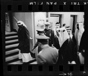 Officers leading men wearing bisht over thawb upstairs