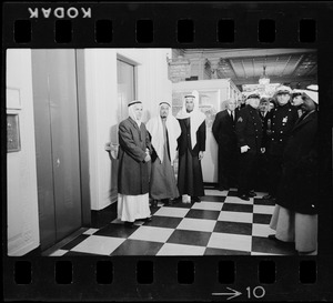 Men including officers waiting by elevators